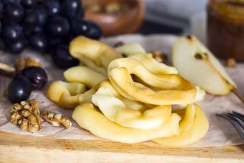 String Cheese, honey, grapes, pears and nuts on wooden board on kitchen Stock Photos