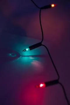 String of Christmas lights glowing at night. Christmas lights close up. Stock Photos