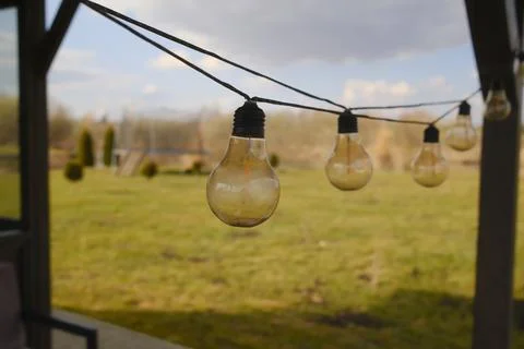 String of decorative hanging light bulbs in a backyard setting Stock Photos