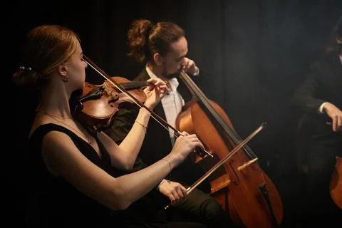 String Ensemble Playing Classical Music in Dark Studio Stock Photos
