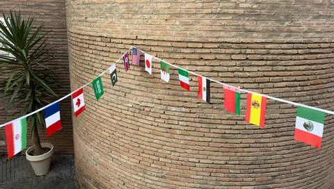 A string of flags hangs on a brick wall Photos