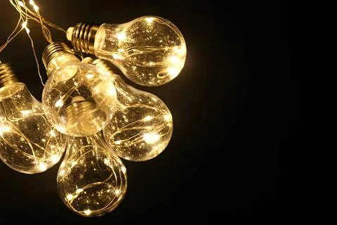 String of glowing light bulbs hanging in darkness Stock Photos