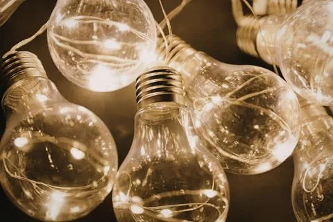 String of glowing light bulbs hanging in warm string lights Stock Photos