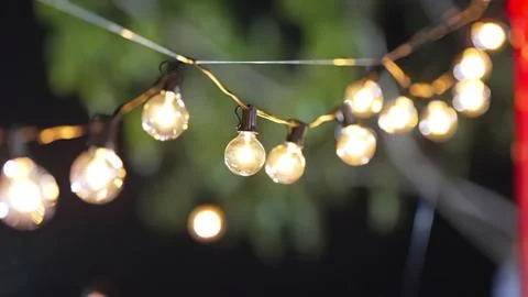 String of glowing outdoor lights hanging in a garden Stock Photos