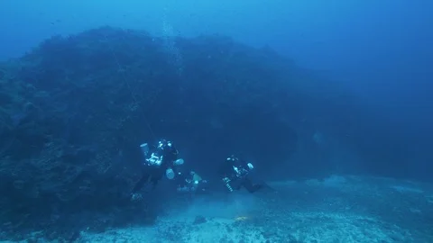 String jellyfish goes away and the divers go toward a rock arch, Med Sea, Italy Stock Footage 115485095