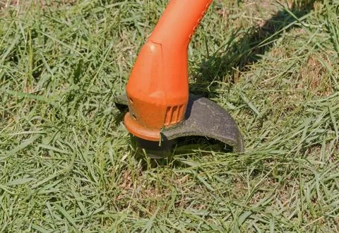 String lawn trimmer mower cutting grass, over a grass background Stock Photos