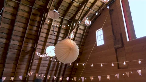 String lights and paper lantern wedding decorations hanging in barn Stock Footage 220456300