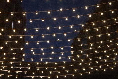 String lights casting a warm, festive glow over falling snow on a dark winter Fotos Stock
