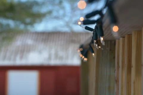 String of Lights on a Deck Railing with a Red Barn in the Background Stock Photos