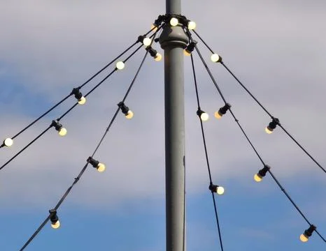 String lights decoration hanging from a street pole against a blue sky Stock Photos
