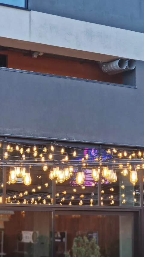 String Lights Glowing Above Outdoor Restaurant Patio During Twilight 스톡 동영상 338993350