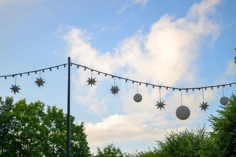String lights hang above green trees under a blue sky Stock Photos