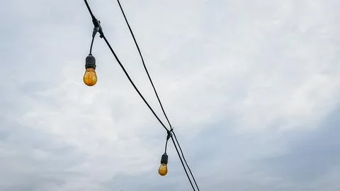 A string of lights hanging from a power line Stock Photos