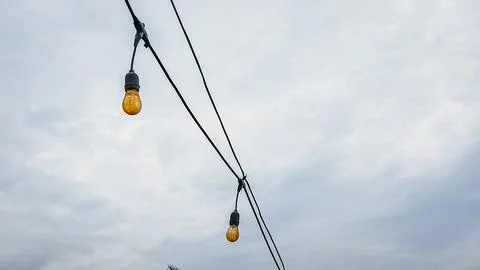 A string of lights hanging from a power line Stock Photos