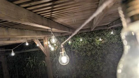 String lights illuminating a garden pergola at night Stock Photos