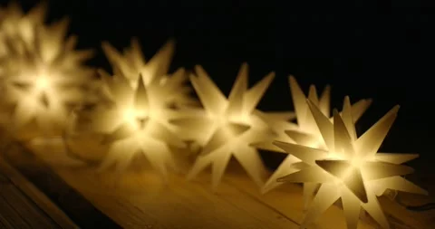 String of many magic star lights on a wooden table illuminate the darkness. Video stock 292671849