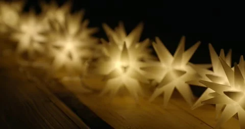 String of many magic star lights on a wooden table illuminate the darkness. Video stock 292671854
