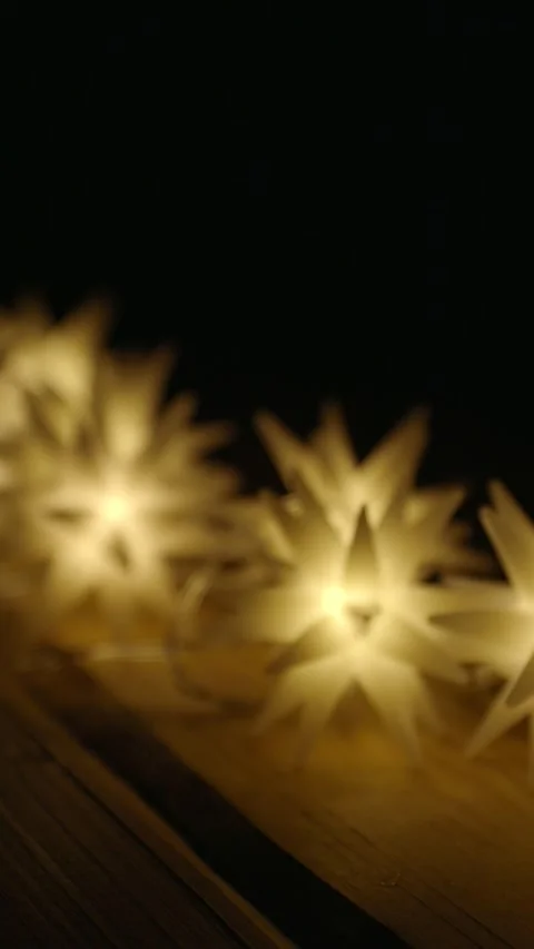 String of many magic star lights on a wooden table illuminate the darkness Video stock 292673648