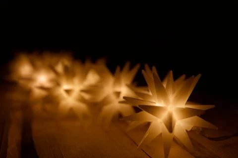 String of many magic star lights on a wooden table illuminate the darkness Stock Photos