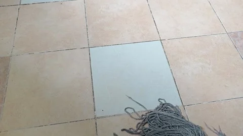 String mop cleans across tiled flooring in a wiping motion. Stock Footage 345589546