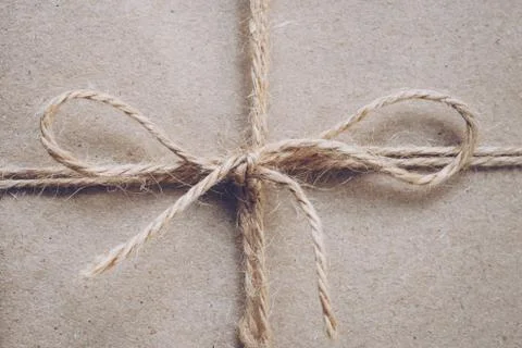 String or twine tied in a bow on kraft paper texture Stock Photos
