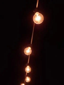 String of outdoor light bulbs at night. Stock Photos
