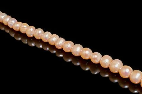 A string of pink pearls on a black background with reflection Stock Photos