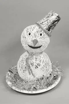 String snowman with foil hat and tinsel on a decorative plate for festive Stock Photos