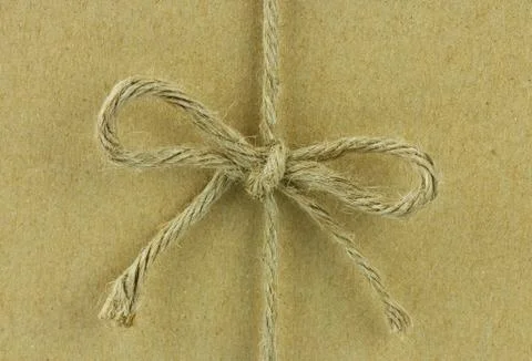 String tied in a bow, over brown recycled paper Stock Photos
