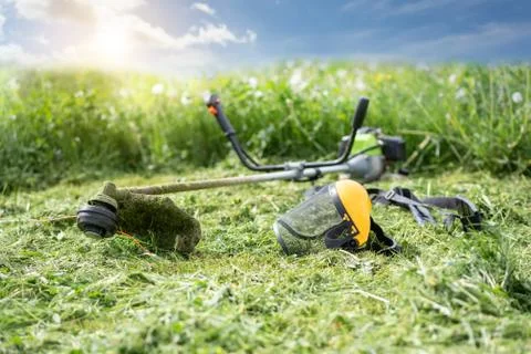 String trimmer and protective face mask on mown grass, sunlight Foto stock
