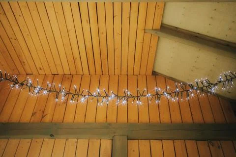 String of white fairy lights draped across wooden beams under a sloped ceil.. Stock Photos