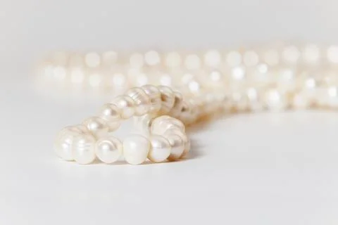 A string of white pearls close-up with soft focus on white. Stock Photos