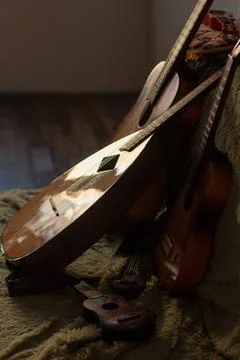 Stringed musical instruments, real and toy, lie on the couch Stock Photos