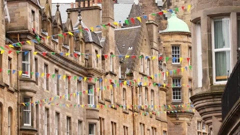 Strings of colorful bunting flags flutter in breeze in front of historic st.. Vídeos de archivo 332694463