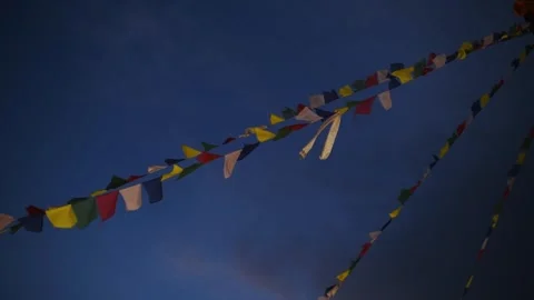 Strings of colourful Tibetan Buddhist prayer flags flutter against a deep blue Video stock 344530469