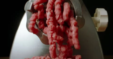 Strings of fresh ground meat falling down grinder is working. Close-up of Video stock 245521098