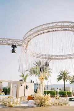 Strings of LEDs hang from a round spotlight stand above a wooden stage decorated 스톡 사진