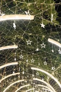 Strings of tiny star lights hang across curved frames in a bright display, .. Foto stock