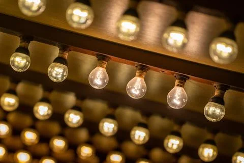Strings of vintage light bulbs casting a warm glow in a cozy indoor setting Stock Photos