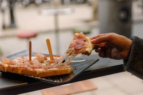 Stringy mozzarella cheese bruschetta slice lifted by hand of woman eating bru 스톡 사진