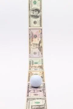 Strip of different us dollar banknotes and white golf ball 库存照片