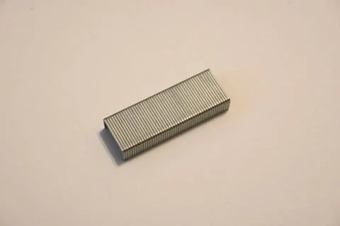 Strip of stapler staples on a plain surface Stockfoto's