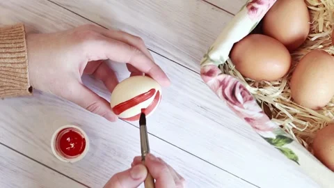 Striped Easter egg. Color the egg with red paints, top view Video stock 233602026