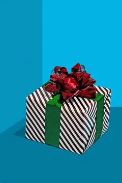 Striped gift box with red bow on blue surface Stock Photos
