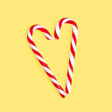 Striped heart shaped lollipops on yellow background Stock Photos