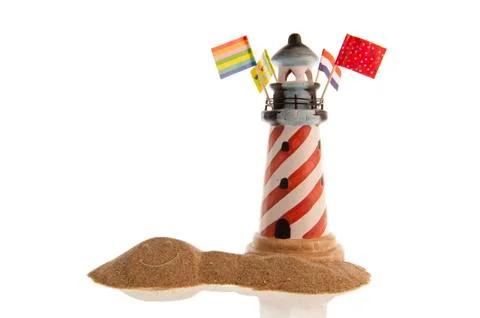 Striped lighthouse, assorted flags, smiley face in sand Stock Photos