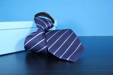 Striped pattern necktie folded with gift box on blue background single object cl Stockfoto's
