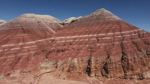 Striped red and white rock formations rising beneath blue sky in Altyn Emel Stock Footage 345410093