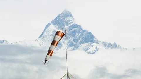 Striped windsock moving around in windy weather with high altitude mountains Stock Footage 121575412