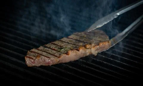 Striploin beef tip getting grilled on a barbeque grill. GRILLING 写真素材
